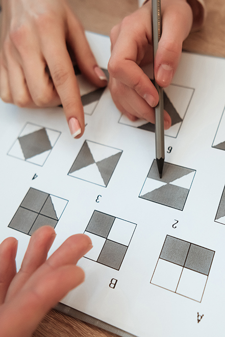 Man Hand Holds Pencil To Make A Mark On Test. A Man Sits At A Ta